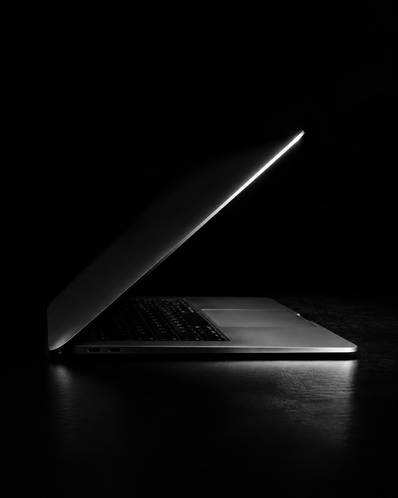 Laptop iluminado lateralmente em ambiente escuro