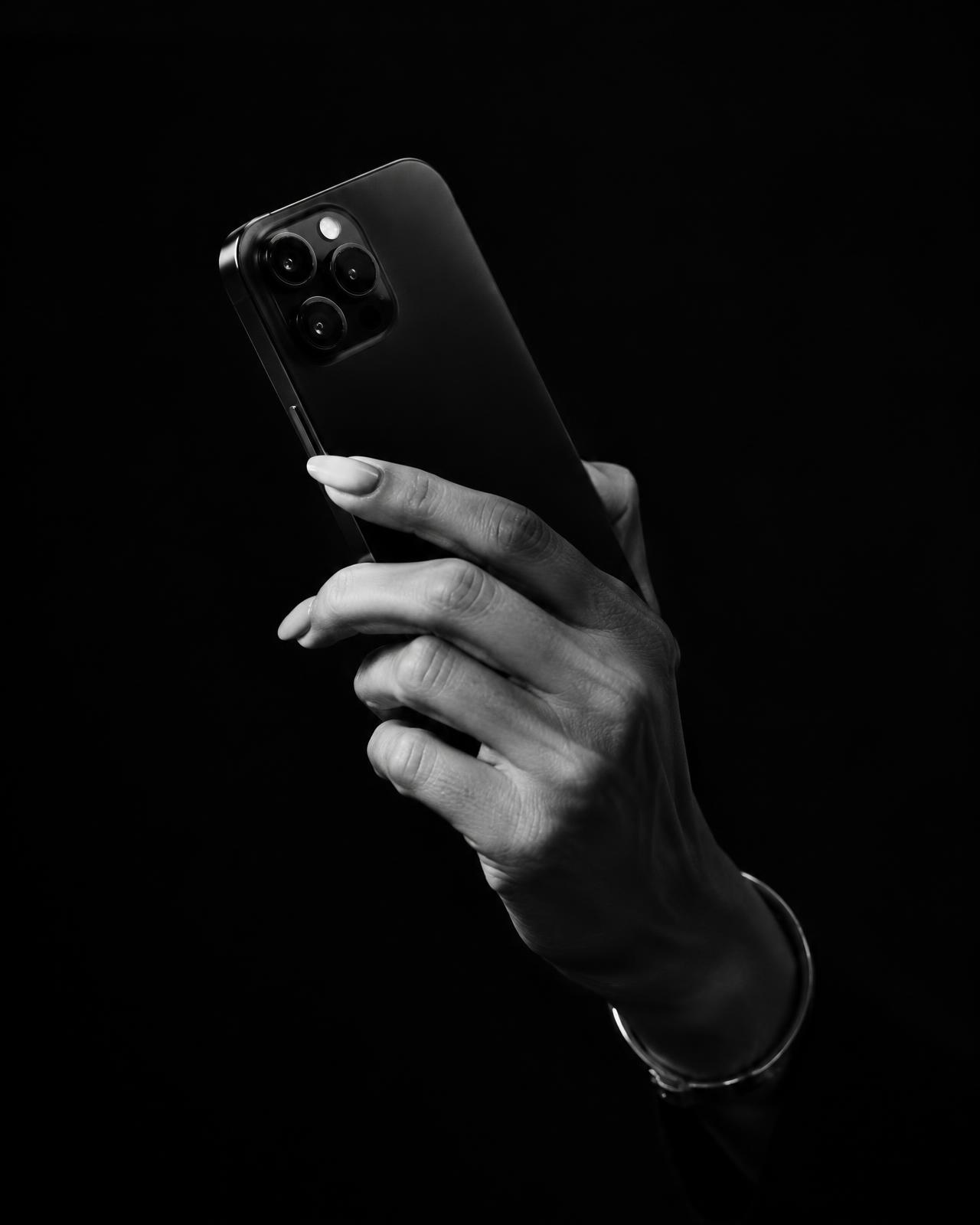 Mão segurando smartphone em fundo preto